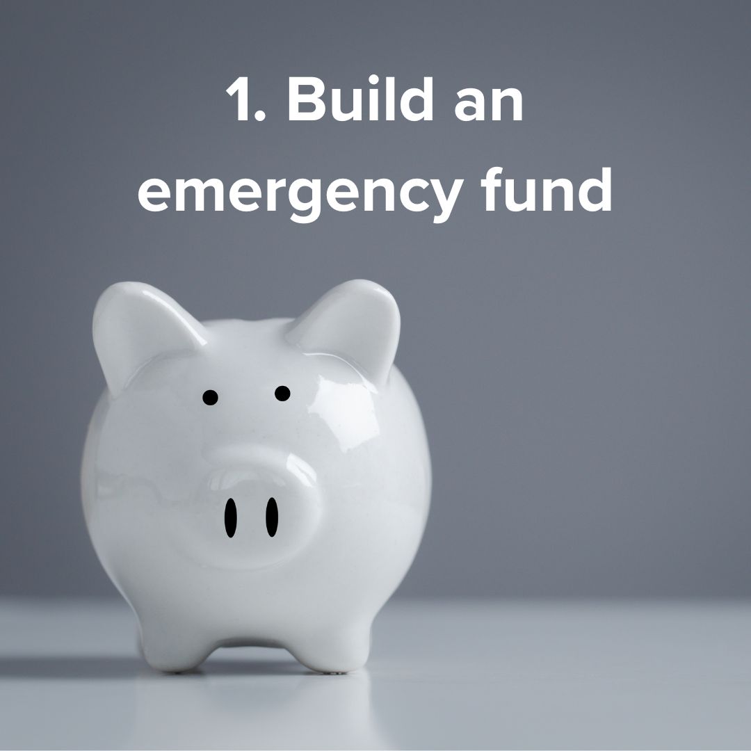 Title in white font at the top says: '1. Build an emergency fund.' White piggy bank on a white counter in front of a dark wall.
