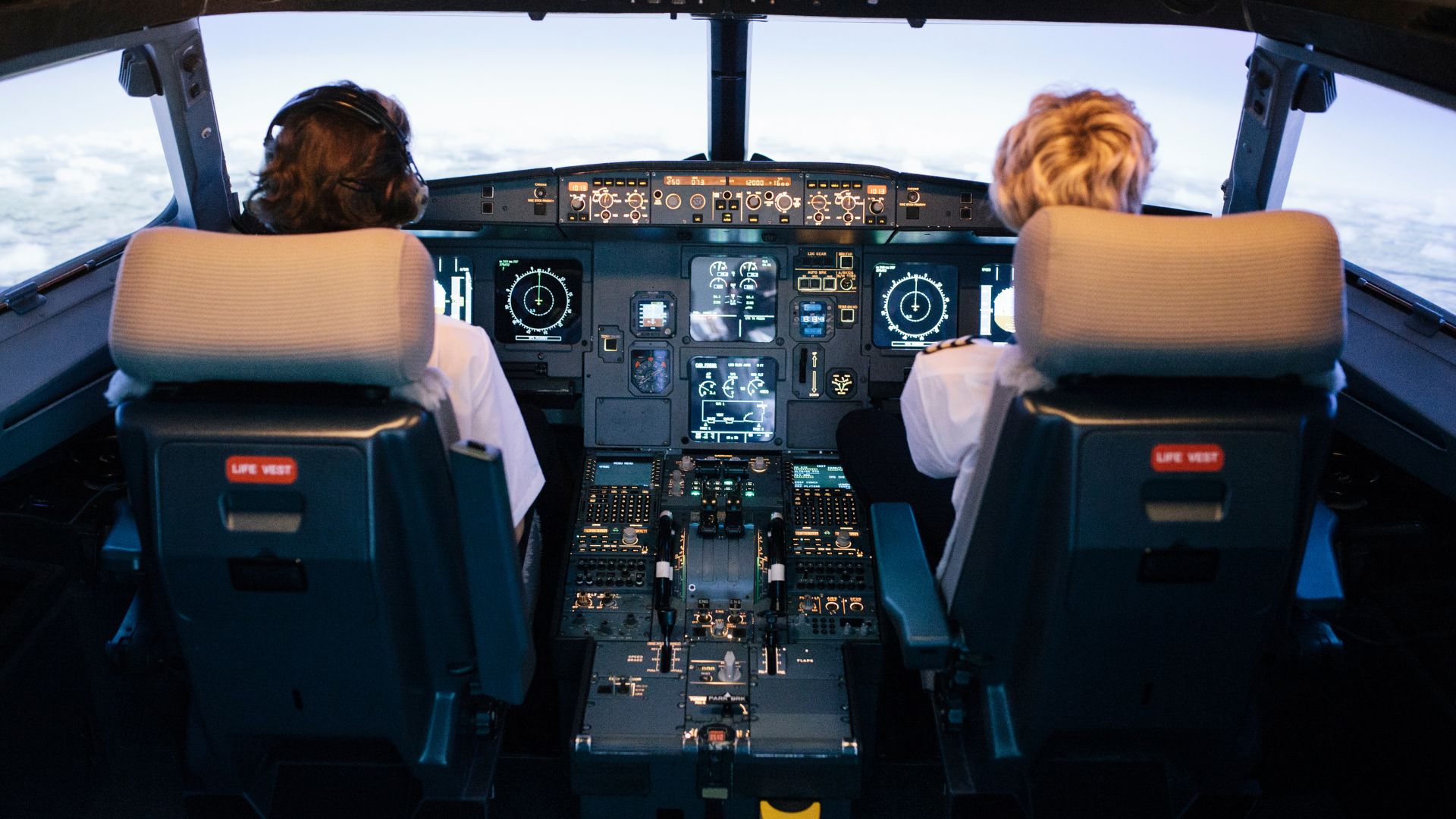 Two female pilots in an airplane cockpit flying the plan above the clouds.