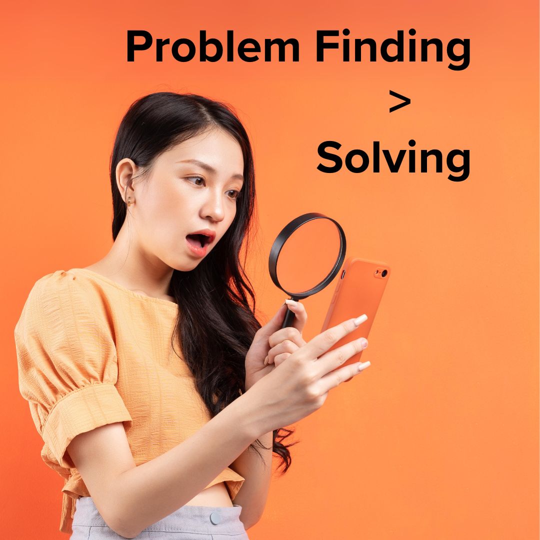 Title 'Problem Finding > Solving' in the upper-right. A woman looks through a magnifying glass to view her phone. The phone is dark orange. Her shirt is light orange. The background is a varying shade of orange.