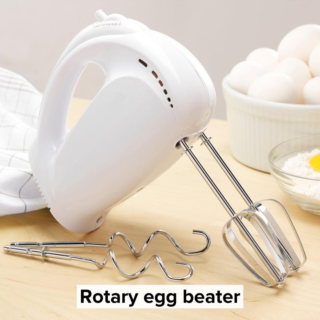 Title 'Rotary egg beater' in black surrounded by a lighter boarder on bottom. The image is of an electric mixer propped up on a table with eggs and flower in the background.