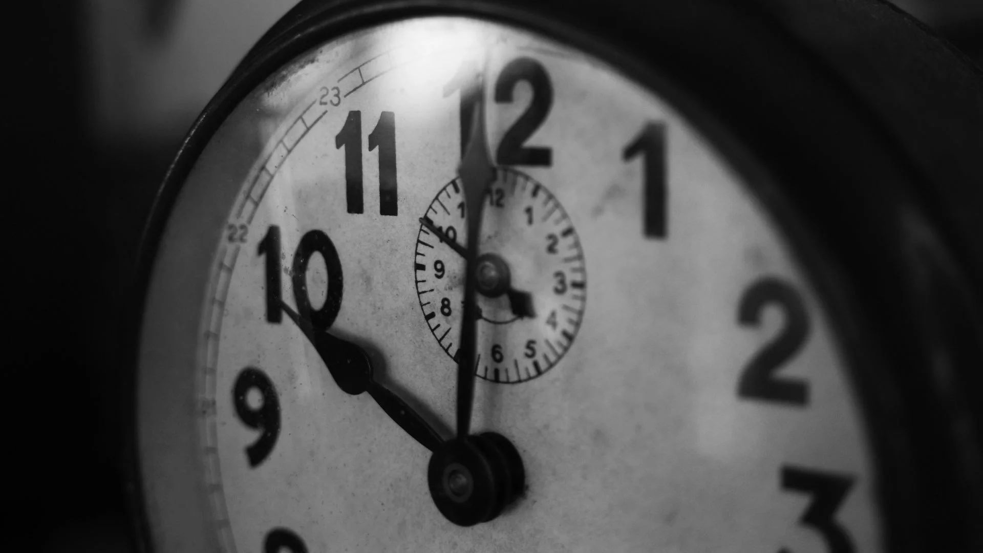 A black and white photo of an analog clock just before 10 o'clock.